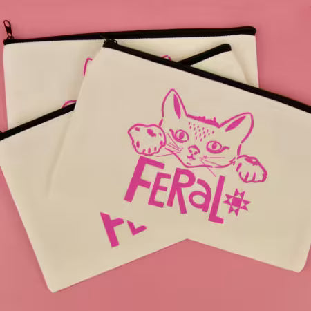 This white canvas zipper pouch features our bold “Feral” design in a hot pink screen print that absolutely pops against crisp white. Finished with a classic black zipper for that clean, high-contrast look. The perfect grab-and-go size for sewing notions, pens, makeup, cords, gift cards, or all the tiny things currently floating at the bottom of your tote. Durable canvas keeps its shape while still being soft enough to toss in a bag.
